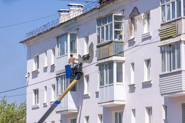 Kako izabrati izvođača za fasadu: 8 pitanja pre dogovora Radnik na platformi renovira fasadu stambene zgrade
